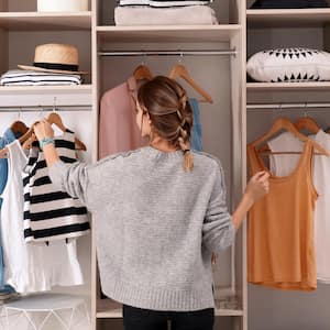 Woman choosing outfit from large wardrobe closet