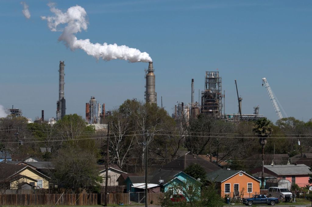 houses in the foreground with an oil refinery in the background