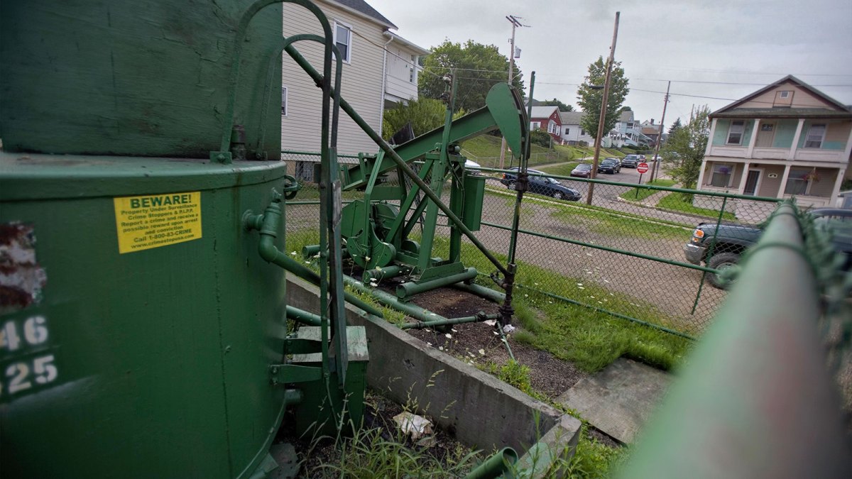 An old oil pumpjack in a yard near residential homes