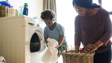 Mother and son take laundry from dryer into basket