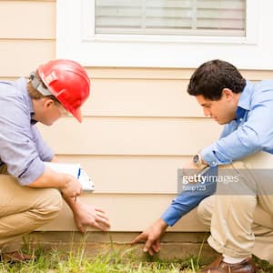 Two professionals inspecting house foundation