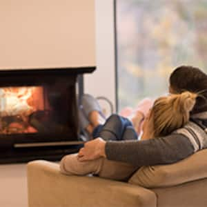 couple sitting in front of fireplace at home