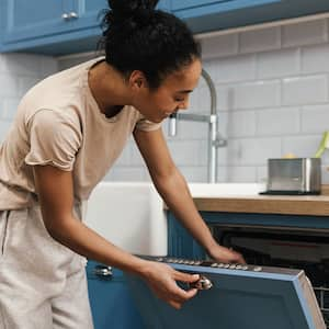 A happy woman opens a dishwasher