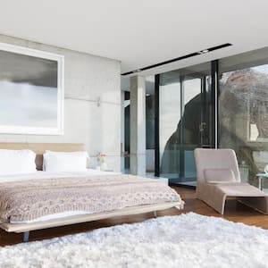 A modern bedroom with amazing views and a white shag rug