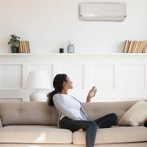 woman resting on sofa turning on air conditioner    