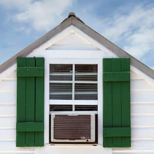 Green painted shutters on a house’s attic window