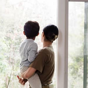 A mother and child look out a window