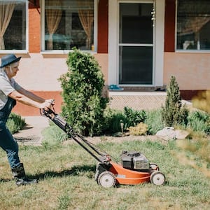 Woman mowing lawn in front of her house