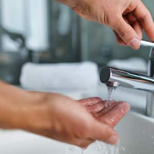 Man testing water pressure in bathroom sink