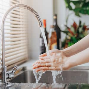 A woman washing her hands in kitchen sink