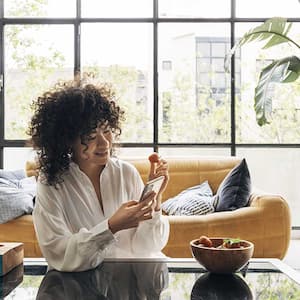 woman holding her phone and eating a strawberry