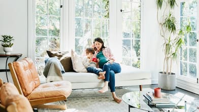 A pregnant mother watching her son playing a  game on her smartphone