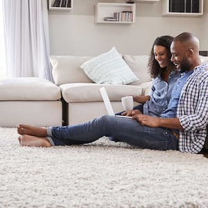 Couple sitting on carpet using laptop