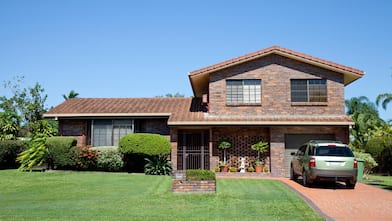 A brown brick house with a landscaped garden