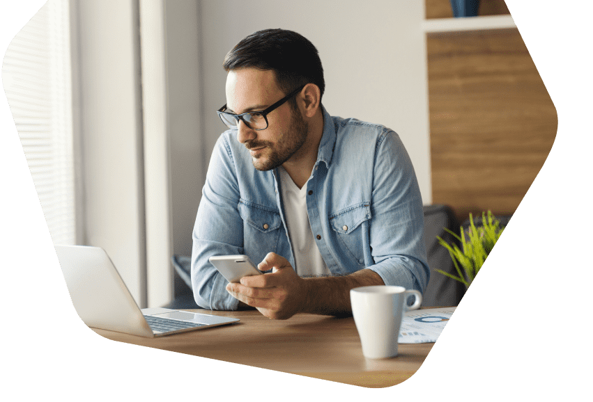 Man at home working using his phone and laptop