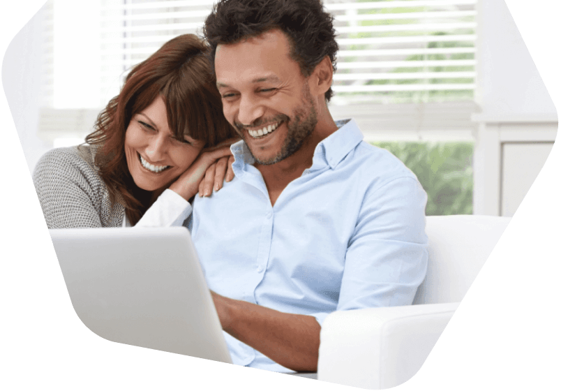 Happy couple smiling while browsing on a laptop