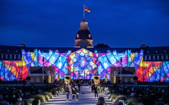 Foto eines bunten Projection Mappings bei Nacht auf dem barocken Karlsruher Schloss.