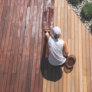 A woman applying protective wood stain