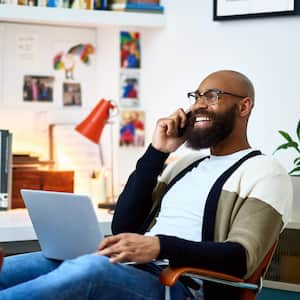 A man talking on his phone while using his laptop