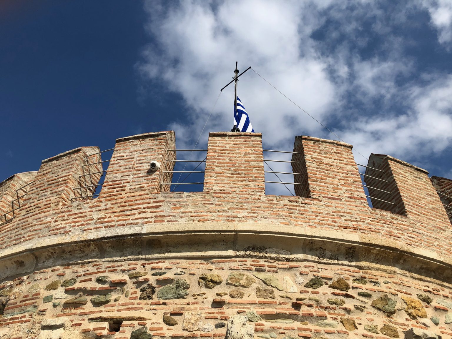 Top of the White Tower with a flag over a blue sky with clouds. Thessaloniki, Greece. Photo contributed by Vagelis to the WordPress Photo Directory.
