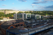 Sheffield bus and coach Interchange is in the foreground, in the bottom left corner is the main entrance. In the centre are long bus stands that form the interchange. Above that is the Digital Campus built upon an unused part of the interchange. In the top left corner is the 1960s Park Hill flats and to the right is Sheffield Station.