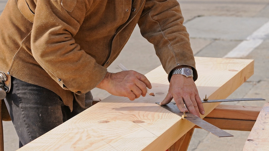 A man measures cuts on a staircase stringer