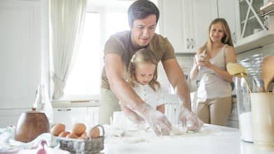 Family baking together in kitchen using countertops as workspace