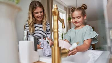 Mom and daughter wash dishes at kitchen sink