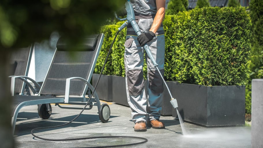 A man cleaning patio with water pressure 