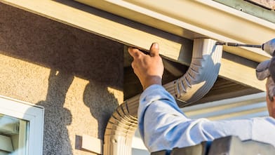 A worker installing new seamless gutters