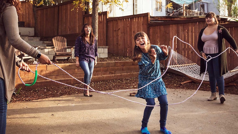 A family jumps rope in a backyard