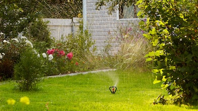 sprinkler watering lawn near house