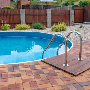 small round home swimming pool with silver stairs and brick patio