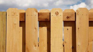 A cedar board-on-board picket fence and a cloudy blue sky