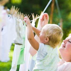 Mother and child hanging clothes on clothesline