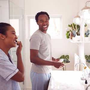 Two adults brushing their teeth in the bathroom