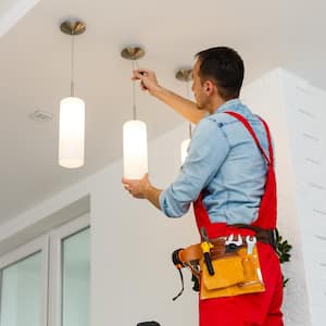 Electrician man worker installing ceiling lamp