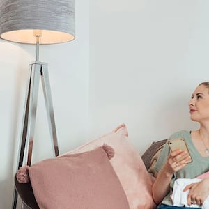 Person looking at a lamp while holding a baby and cellphone