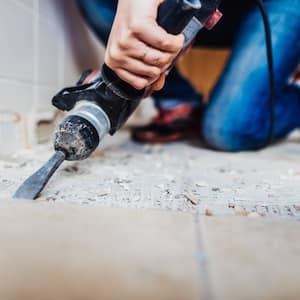 A person removing tile flooring with a power chisel