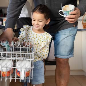 A father helping his daughter to load the dishwasher
