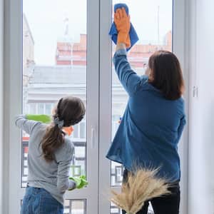 A mother and daughter cleaning tall windows in home