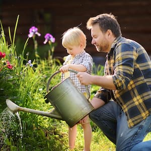 Man and his little son watering flowers