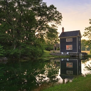 A cottage house next to a beautiful pond