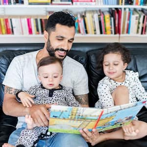 Father reading a book to the children at home