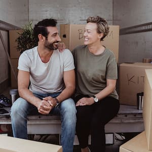 couple sitting on moving truck loading boxes