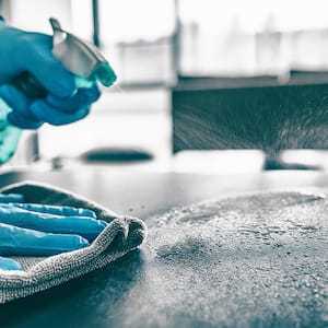 Person cleaning table with cloth and cleaner