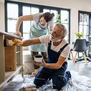 Father and daughter painting together some old furniture