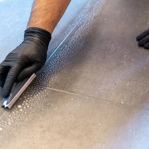 A professional cleaner cleaning grout with a brush