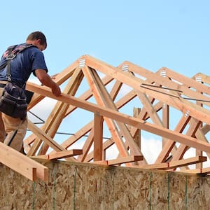 Man building wooden frame on roof.