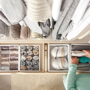 A woman putting away laundry neatly in her closet